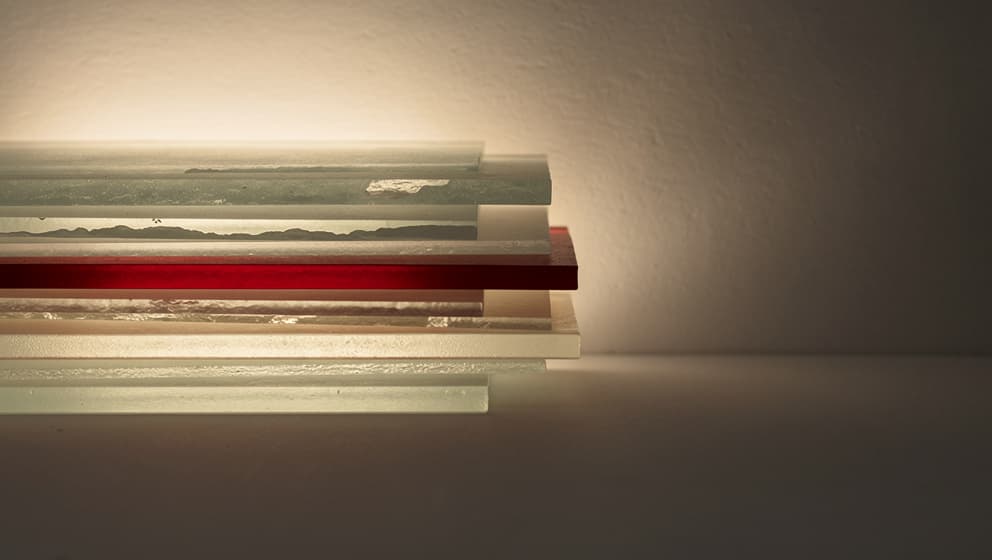 Narrow stack of layered frosted glass panels receding into fog with one panel tinted red, representing the thin Nordic tech talent pipeline